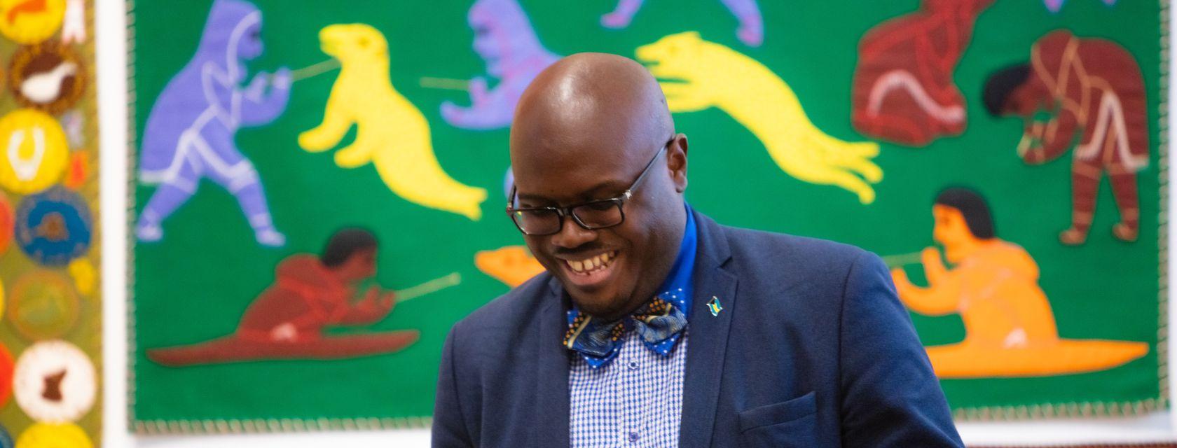 Charles Hamilton at a speaking event standing in front of a colourful mural.