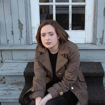 Woman sitting on the steps of an old house.