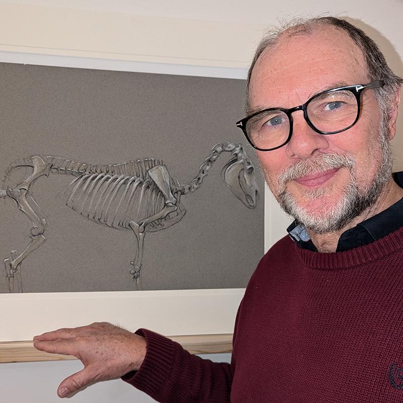 Older man standing in front of a horse skeleton diagram.