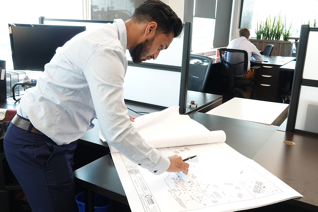 male graduate at work, looking at blueprints