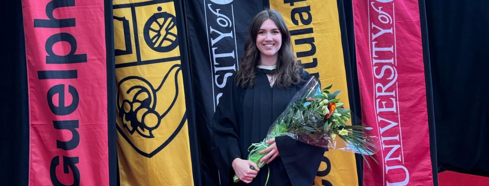 U of G Politcal Science Major Abigail Boorsma posing with flowers at her graduation.