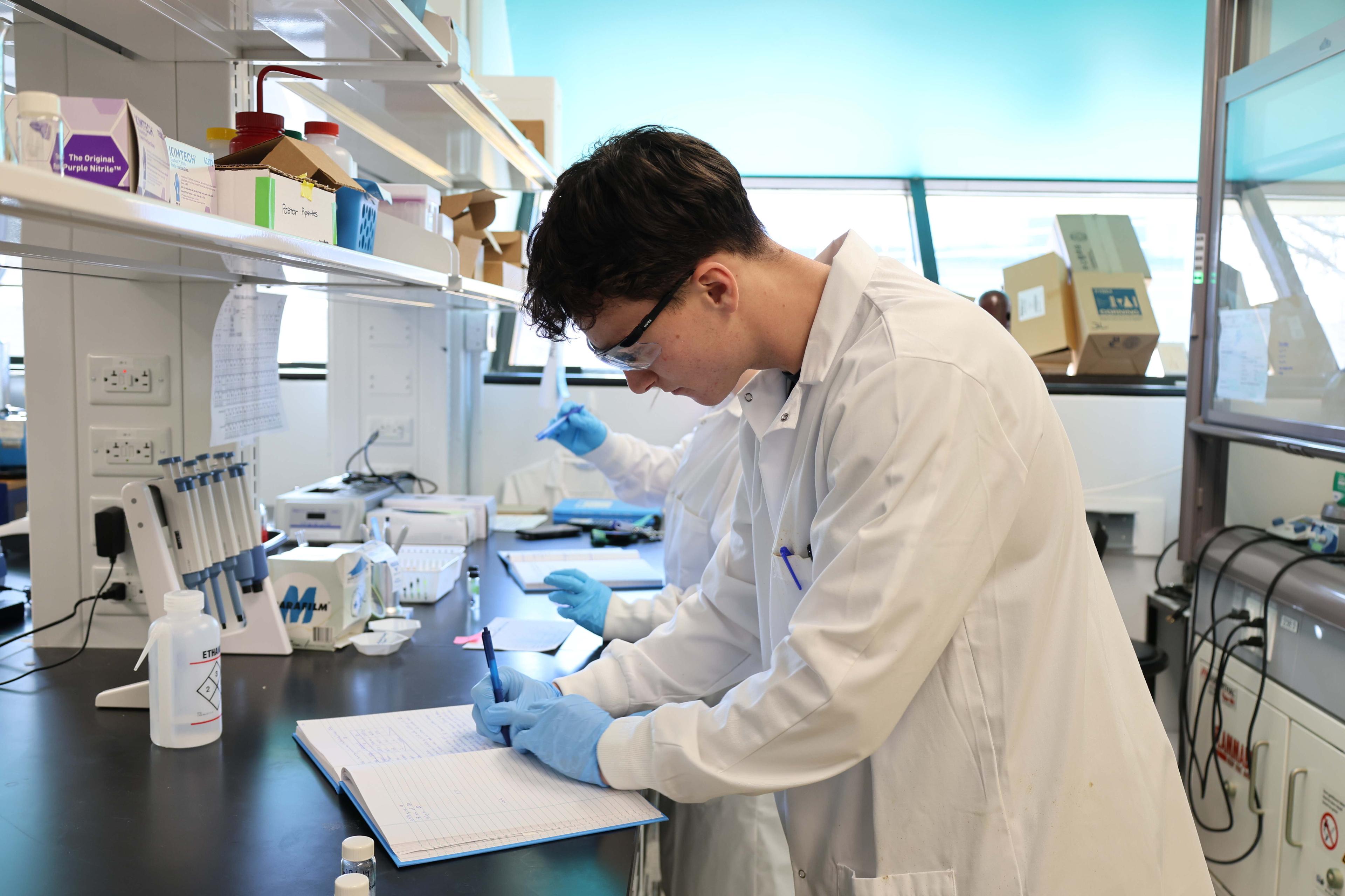 A student in a lab writing on a paper.