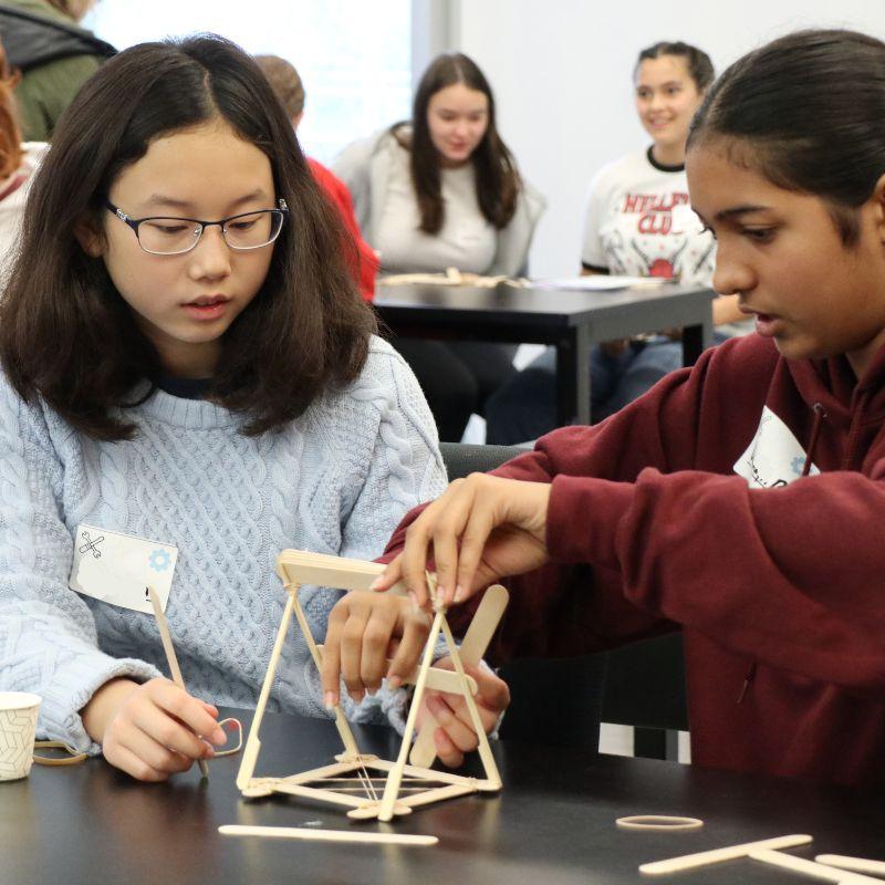 Two Creative Encounters campers build a structure from popsicle sticks