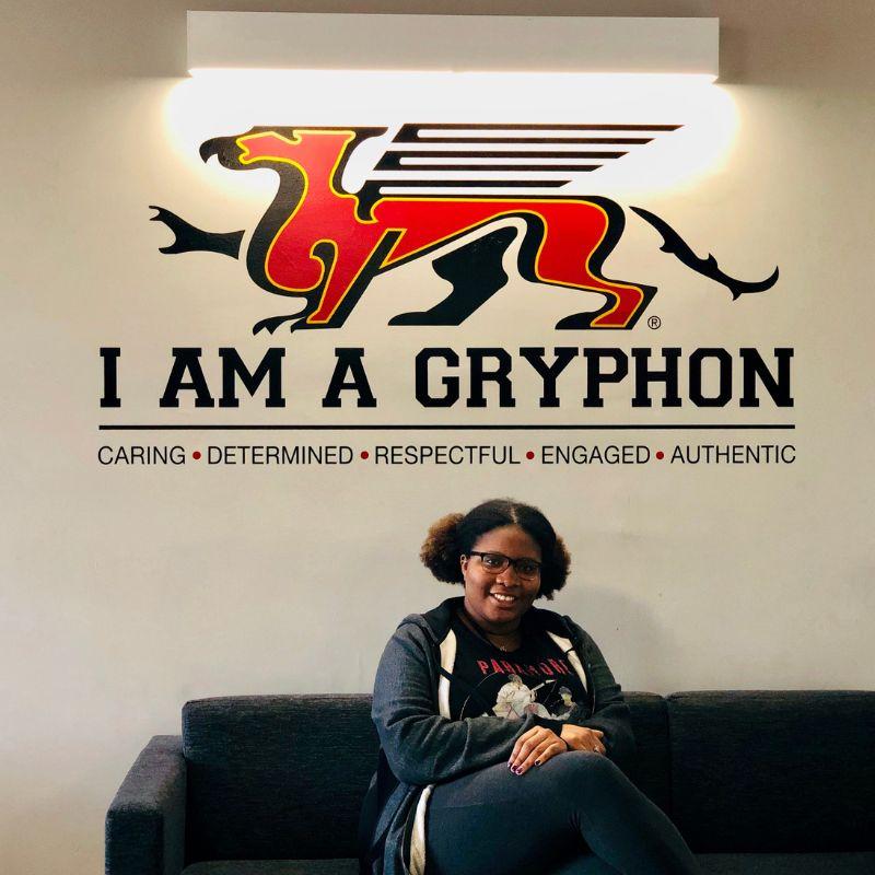 Guelph Grad Kia-Marie Parsons sitting in front of the I am Gryphon sign.