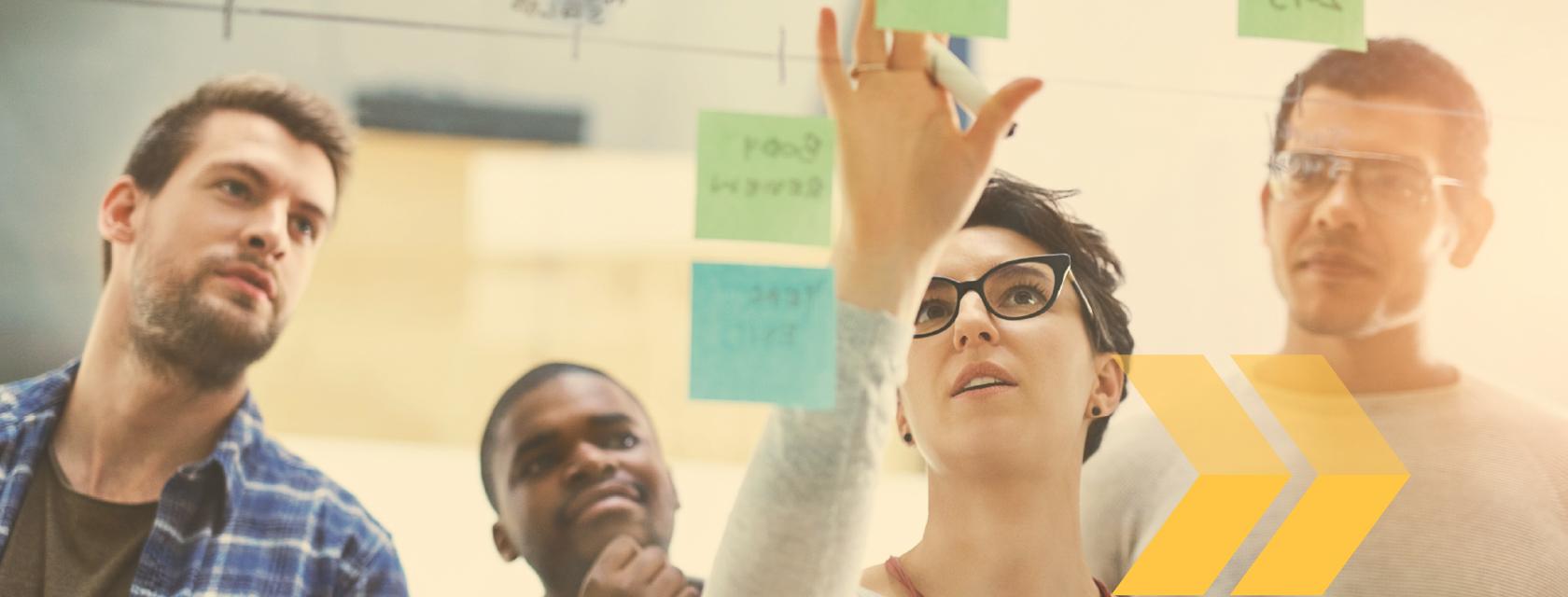Group of people adding sticky notes to a board.