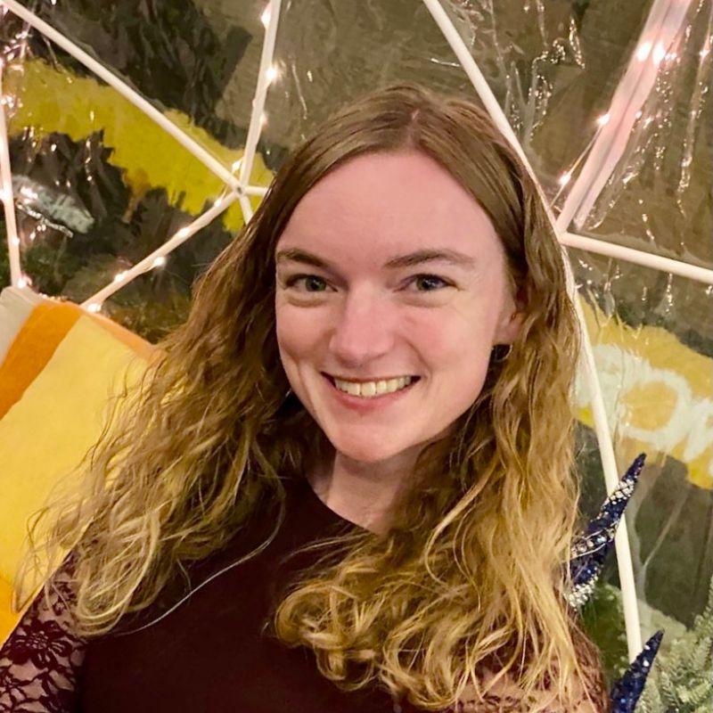 Mathematics grad Rachael Lewitzky smiling while white christmas style lights illuminate the background. 