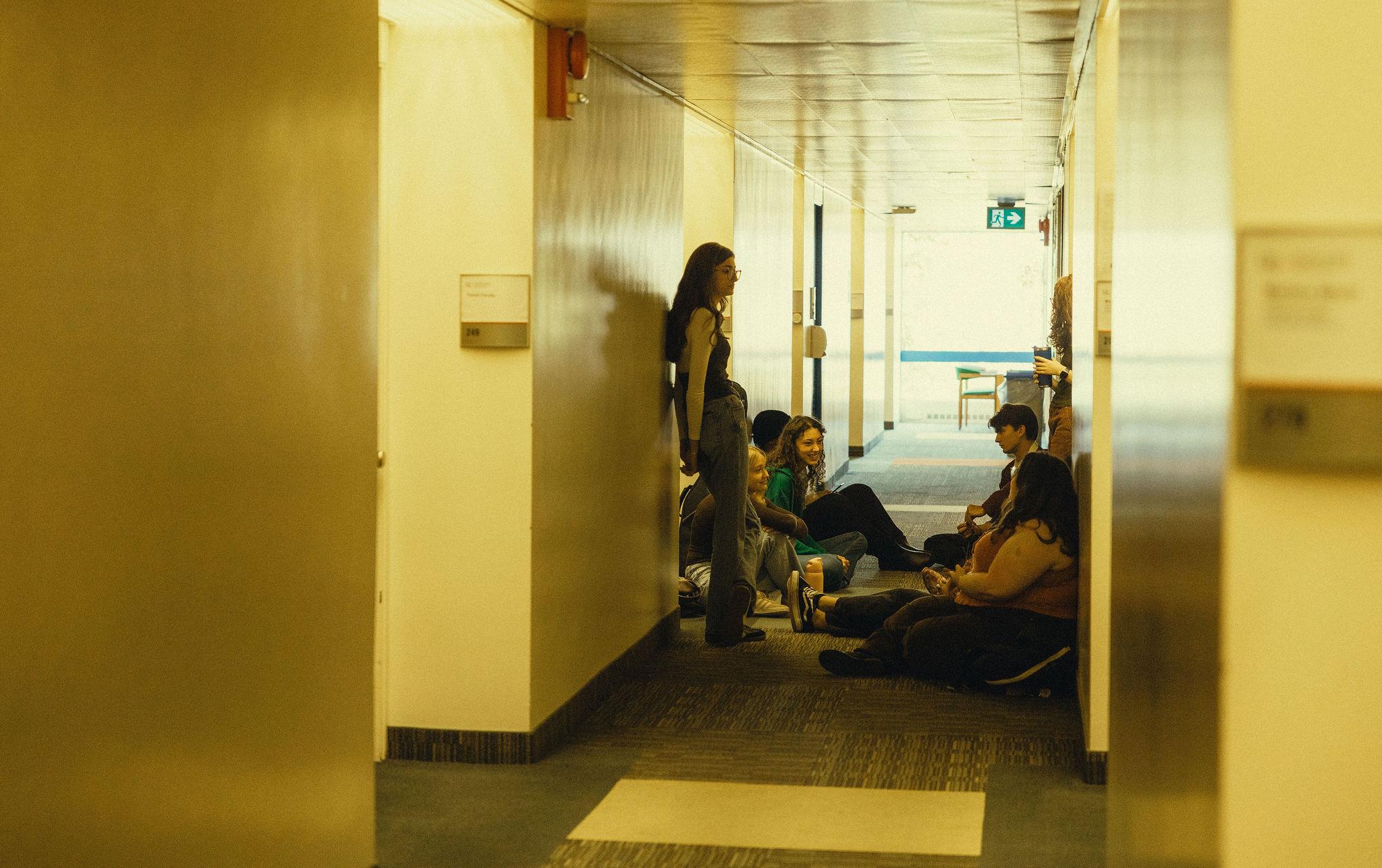 Students sitting in a hallway.