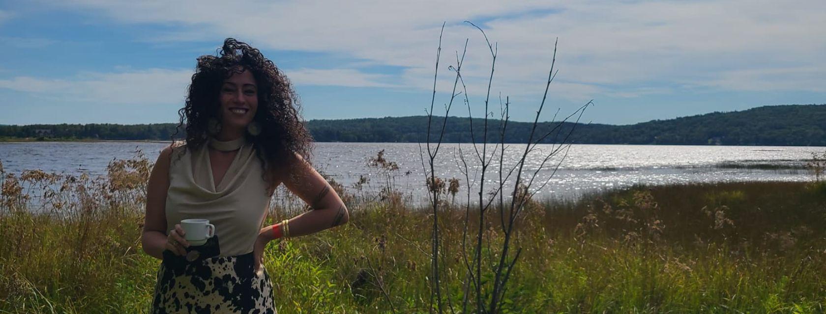 Dr. Mikaela D. Gabriel poses outside near a calm body of water. 