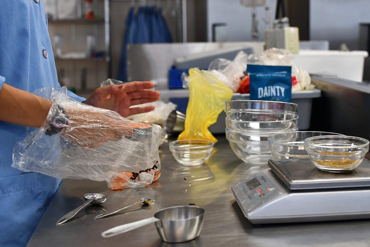 A person cooking with gloves on