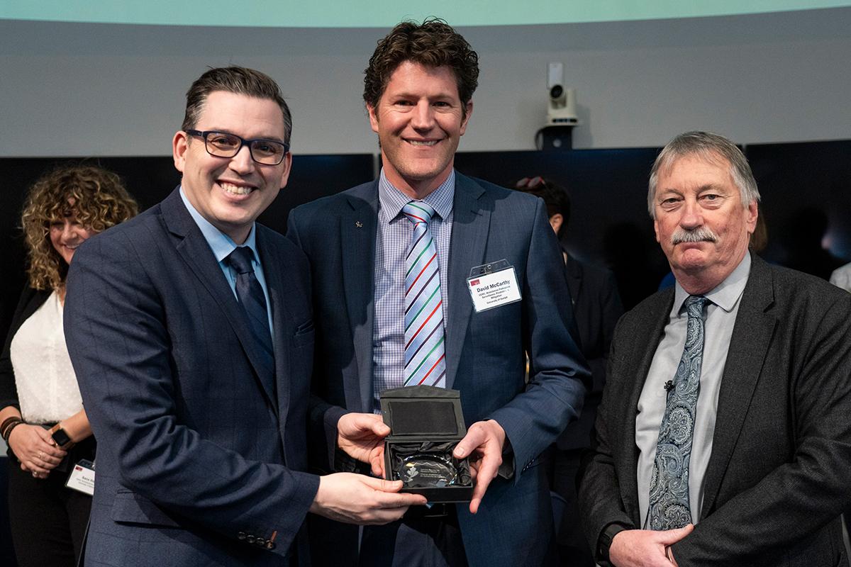 Three men holding an award