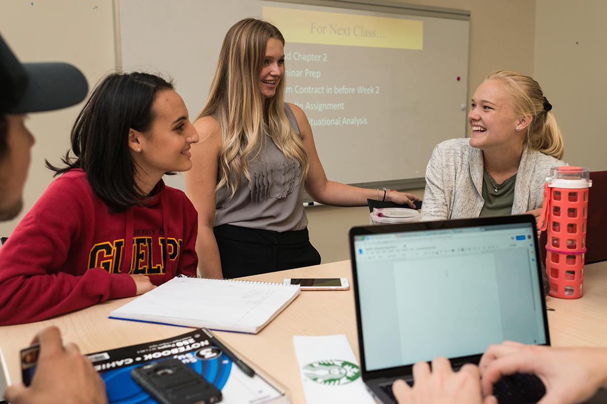 Three students in studying together with a laptop