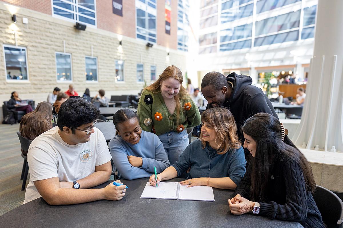 A group of students writing in a notebook at a table