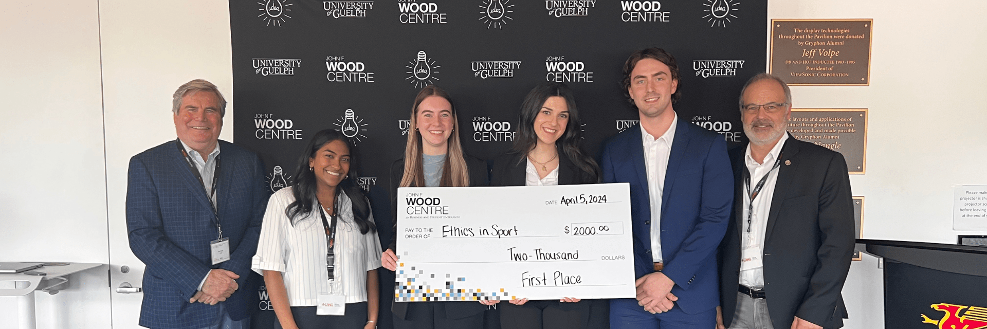 4 students standing with 2 professors and large cheque