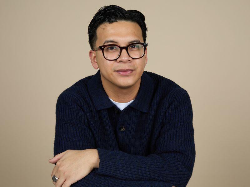 Business Grad Matthew Martin poses for a picture wearing glasses and a v neck sweater.