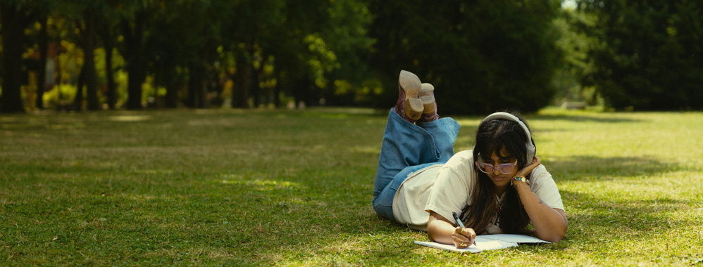 Student laying on Johnston green and studying