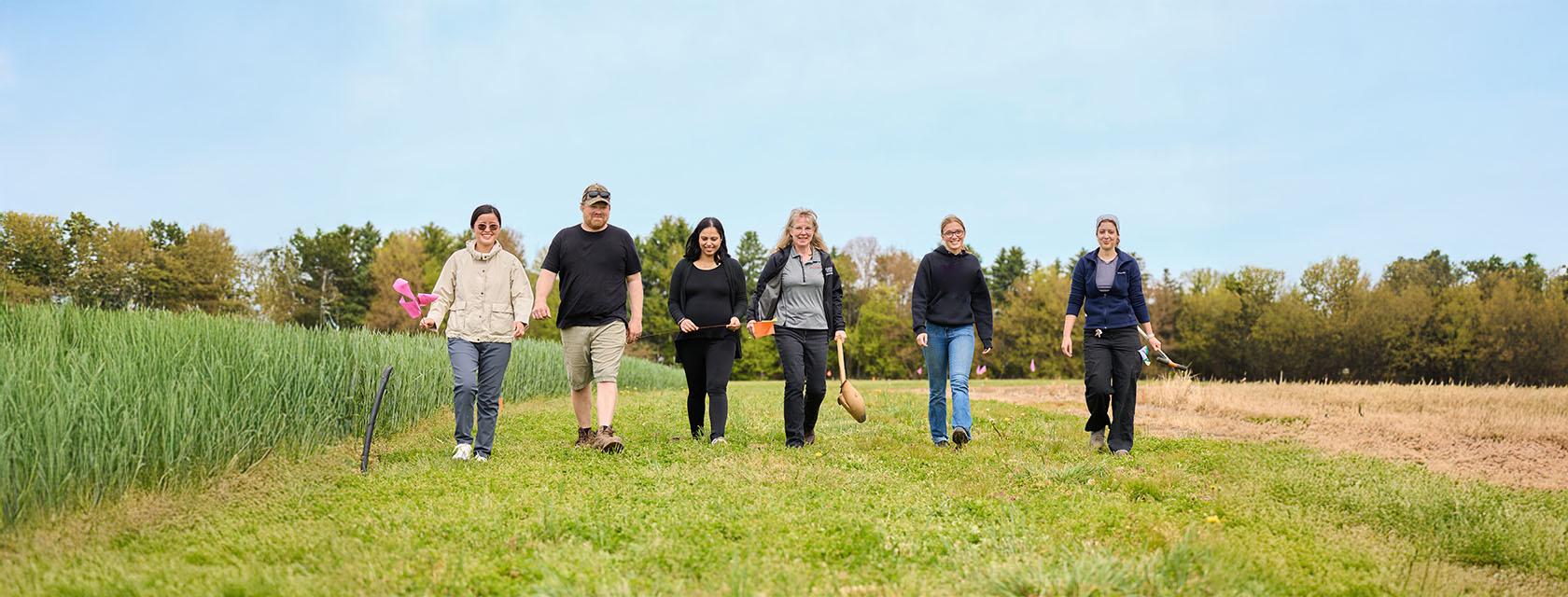 Six people walking towards the camera in a field.