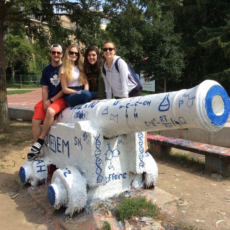 Guelph Grad Laura Martin poses on the cannon with her classmates. 