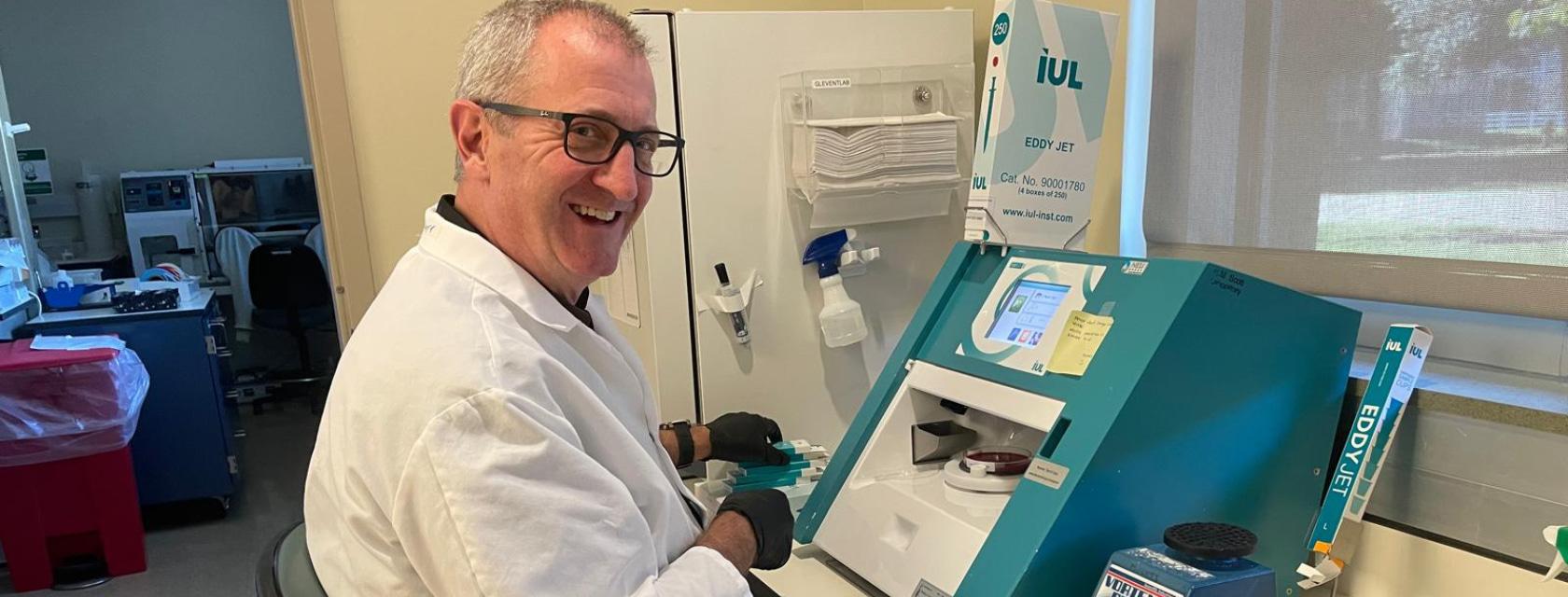 A man wearing a white lab coat working in a lab setting