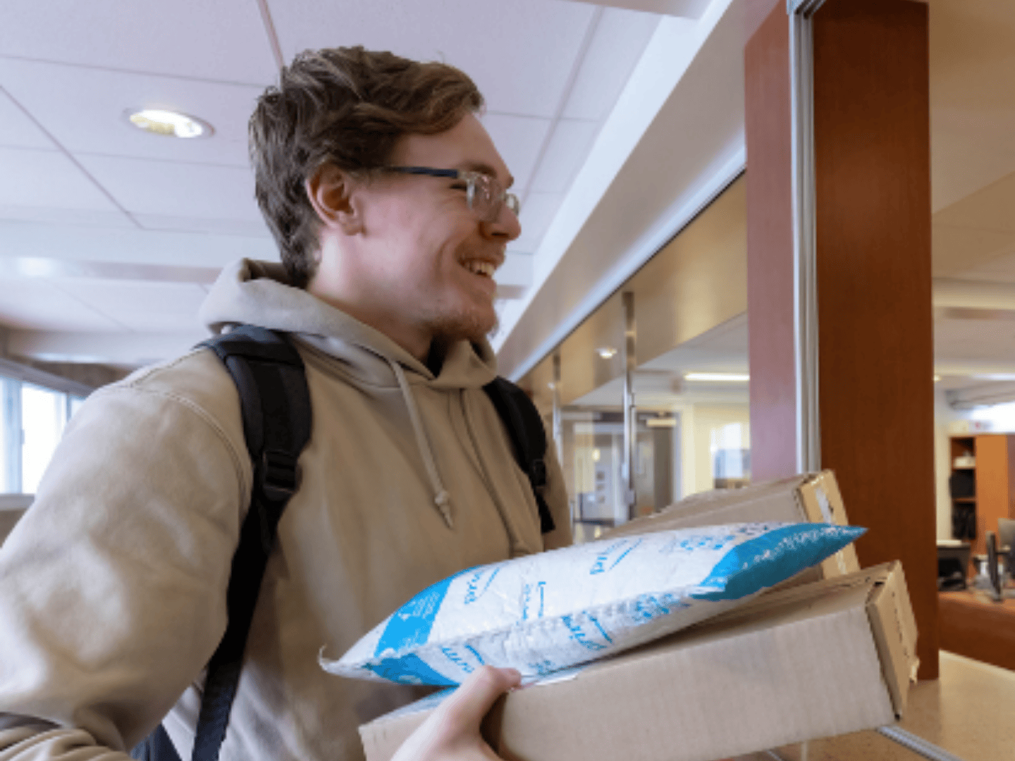 student picking up two packages from a residence desk, one box and one envelope