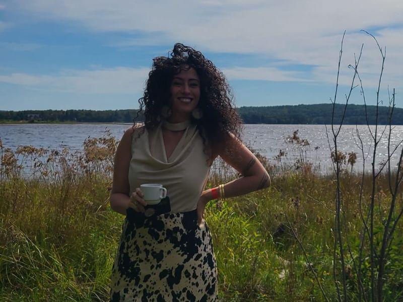 Dr. Mikaela D. Gabriel poses outside near a calm body of water. 