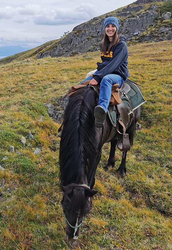 Young woman sitting on a horse in the mountains.