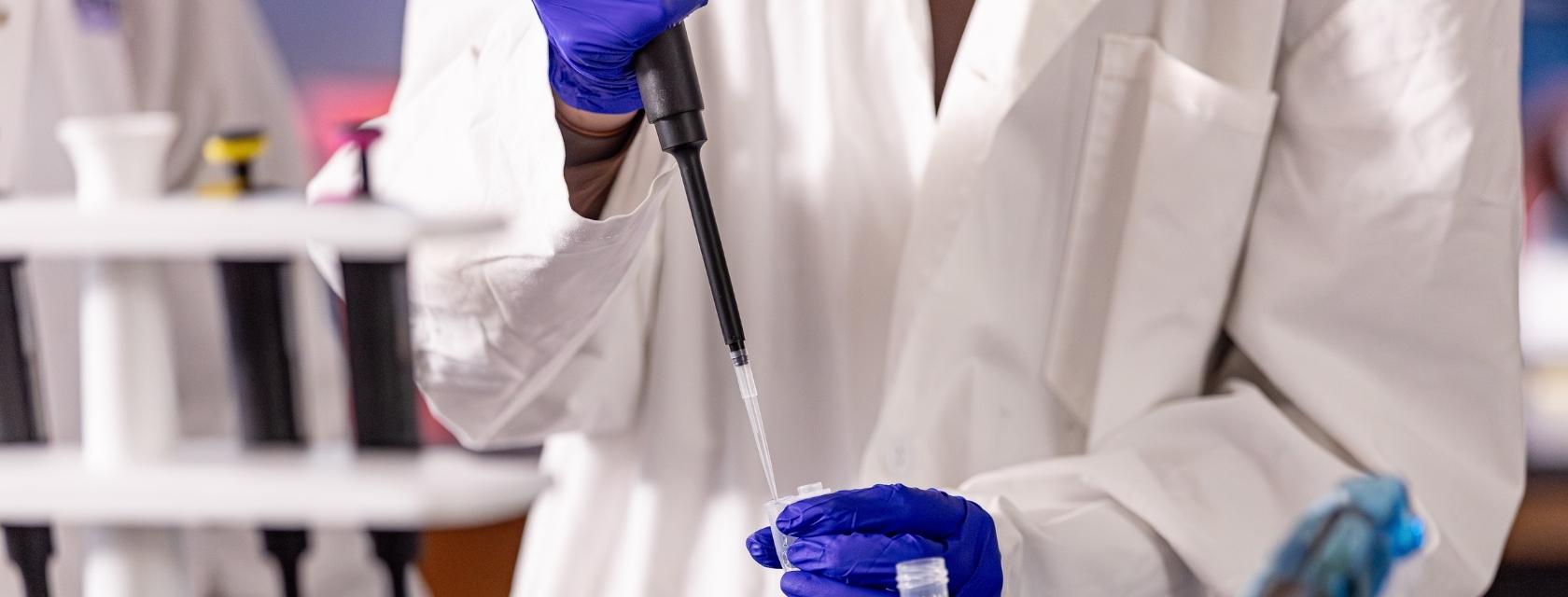 student in lab coat pipetting