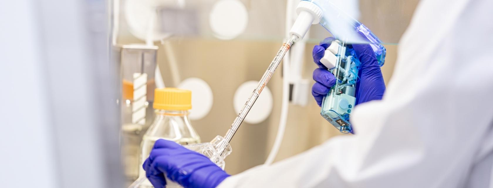 student pipetting in a hood