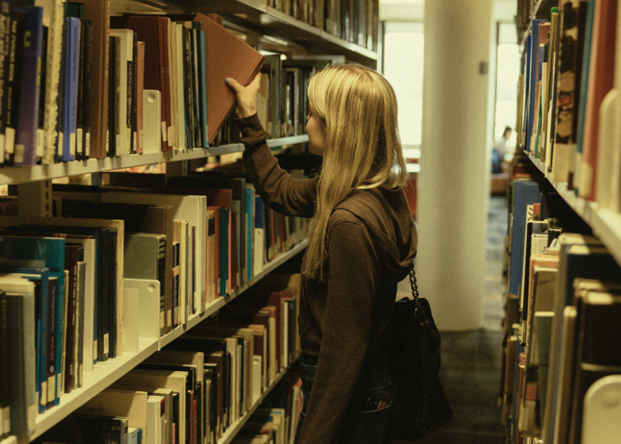 Student reaching for books in the library