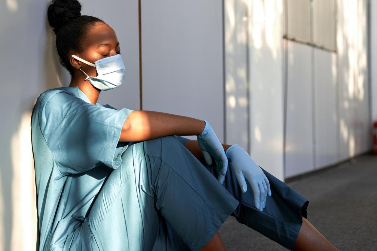 hospital worker sitting on floor looking exhausted. 