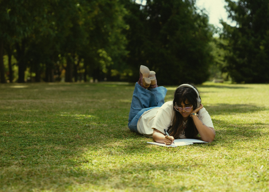 Student laying on Johnston green and studying
