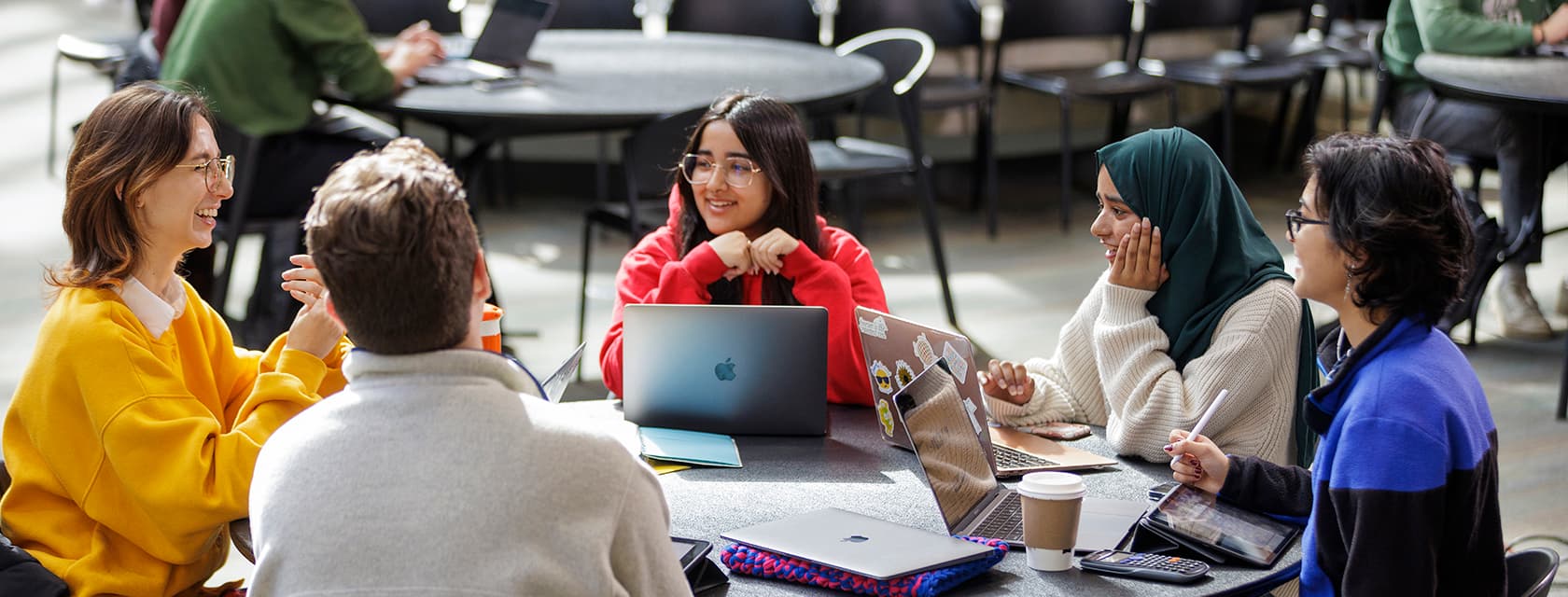 Group of students sitting around a table talking.