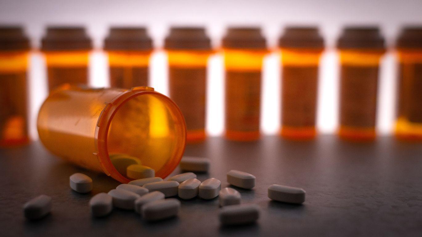 A medication bottle tipped on the side with pills spilling out.