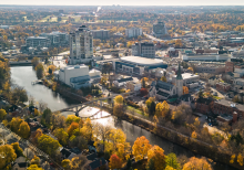 Aerial view of downtown Guelph in autumn, featuring the Speed River, historic buildings, bridges, and trees with vibrant fall foliage.