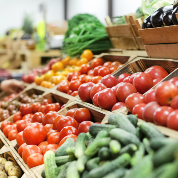 Boxes of fresh fruits and vegetables are displayed on a table at a market.