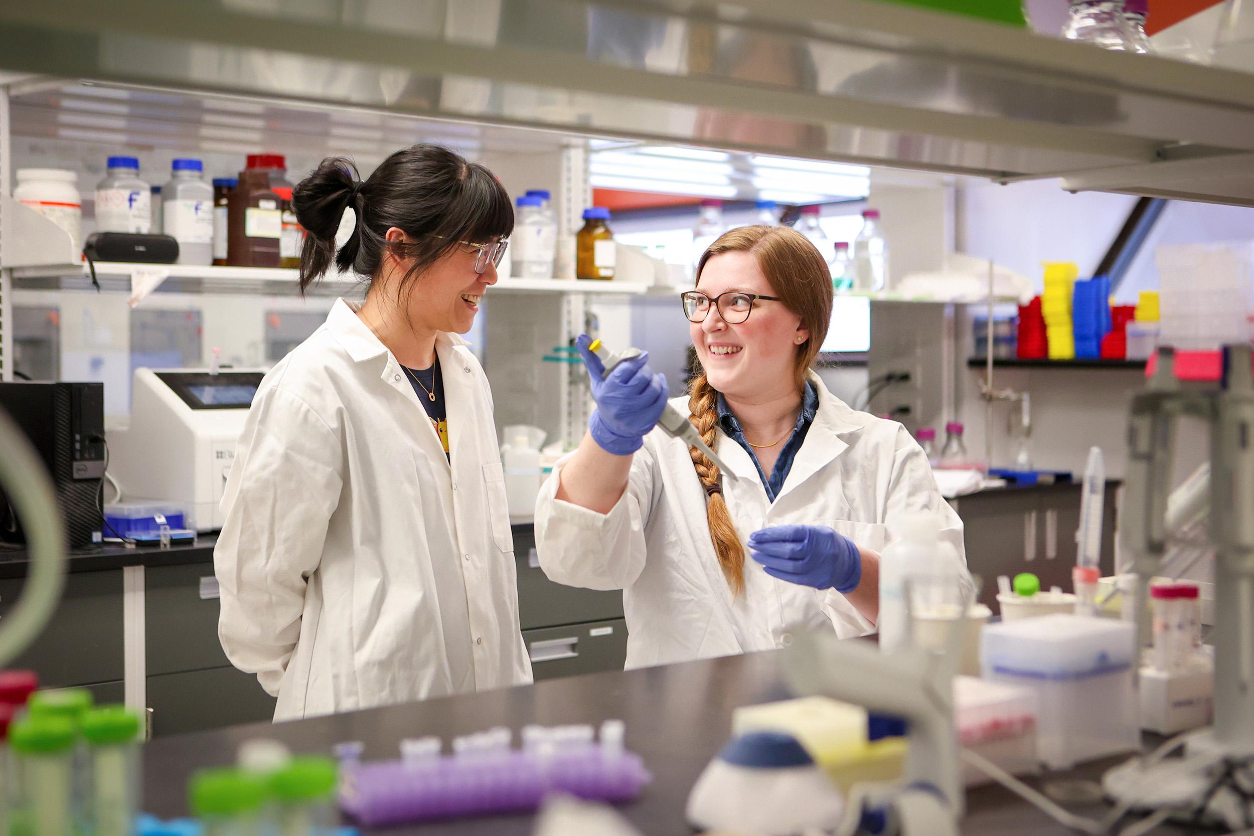 Dr. Rui Huang, left, and Megan Black, a Chemistry PhD student, are working together in a lab while wearing personal protective equipment
