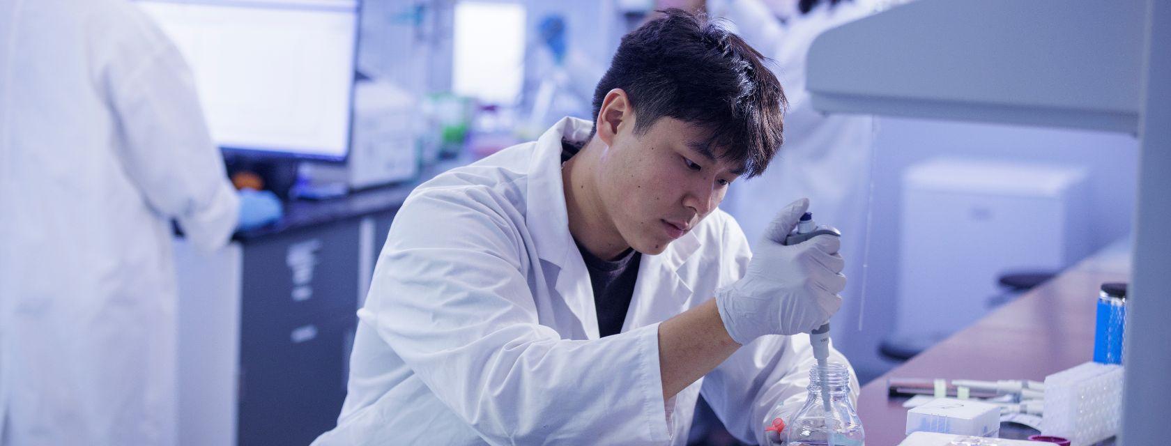 Student in lab using a pipette to transfer liquids