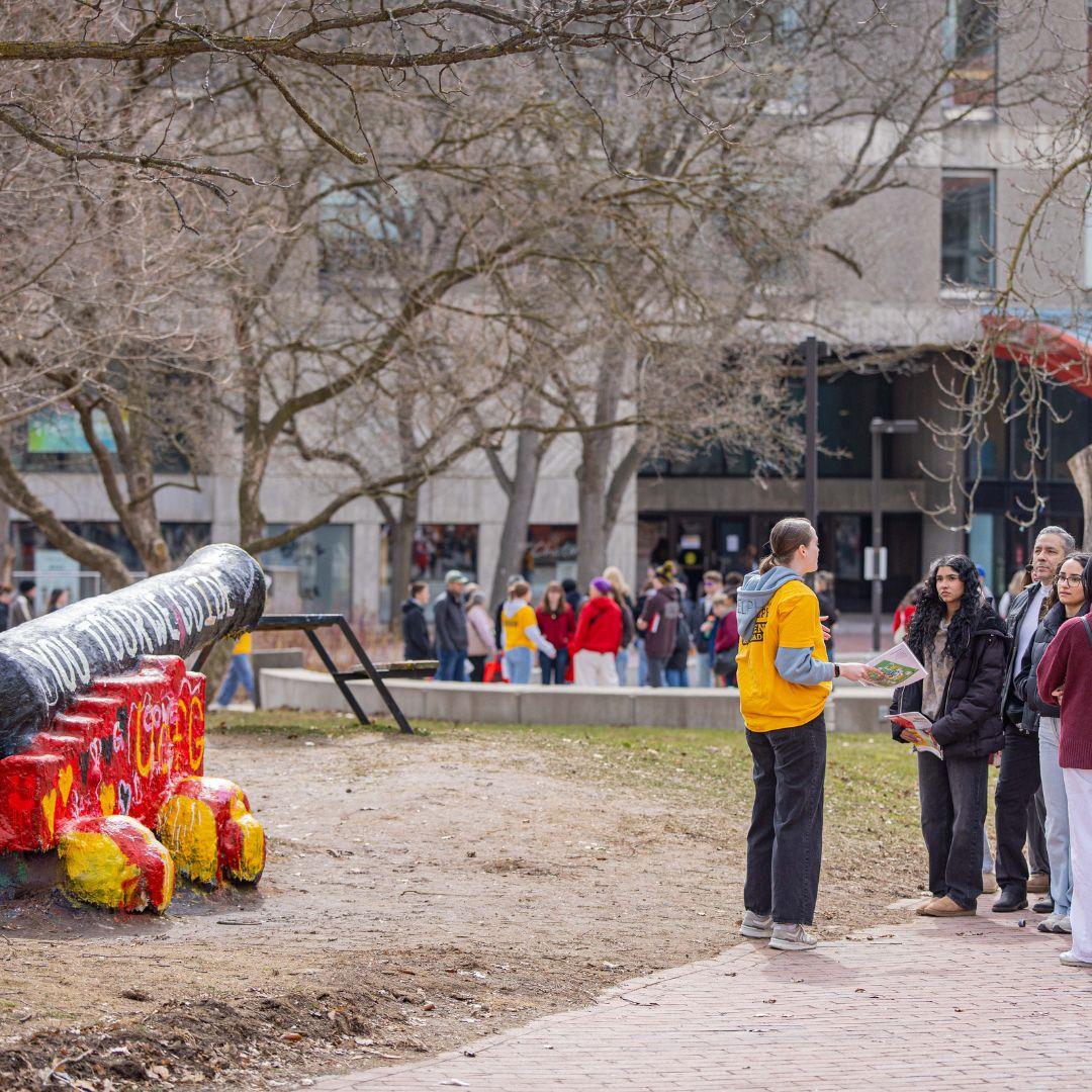 A student tour guide leads a tour in front of the cannon.