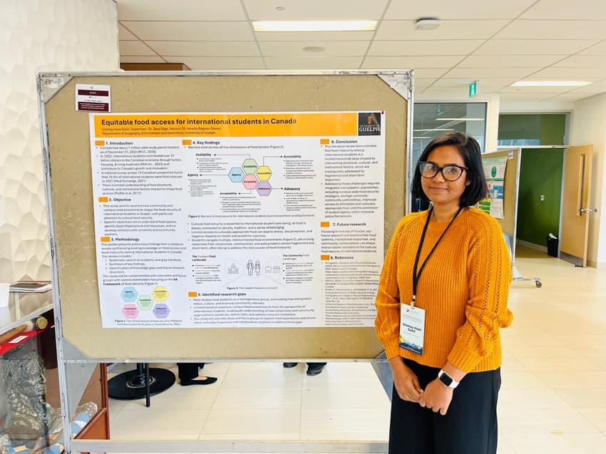 Researcher standing next to a poster presentation on food access for international students at an academic event.