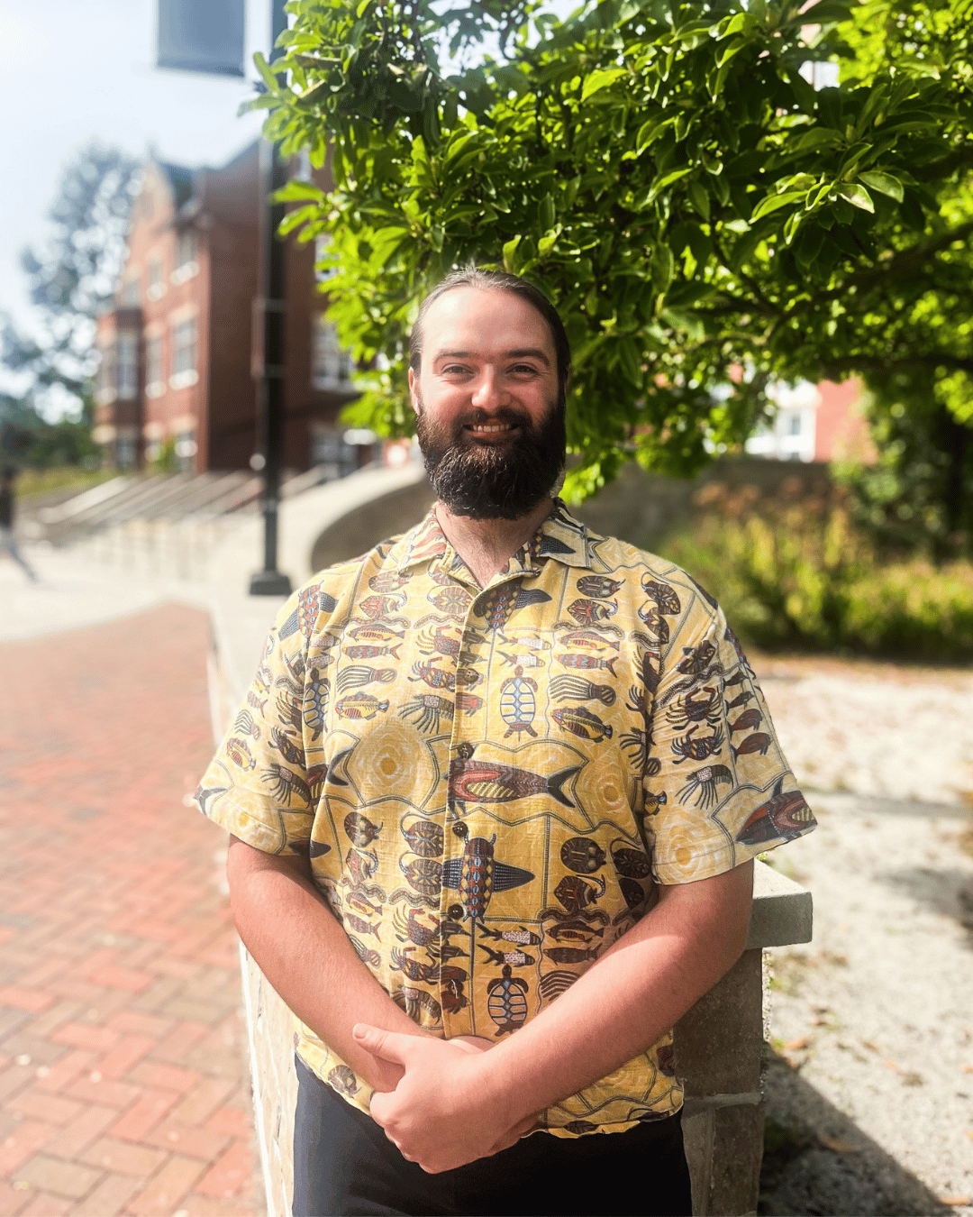 A student smiling at the camera with a tree behind them