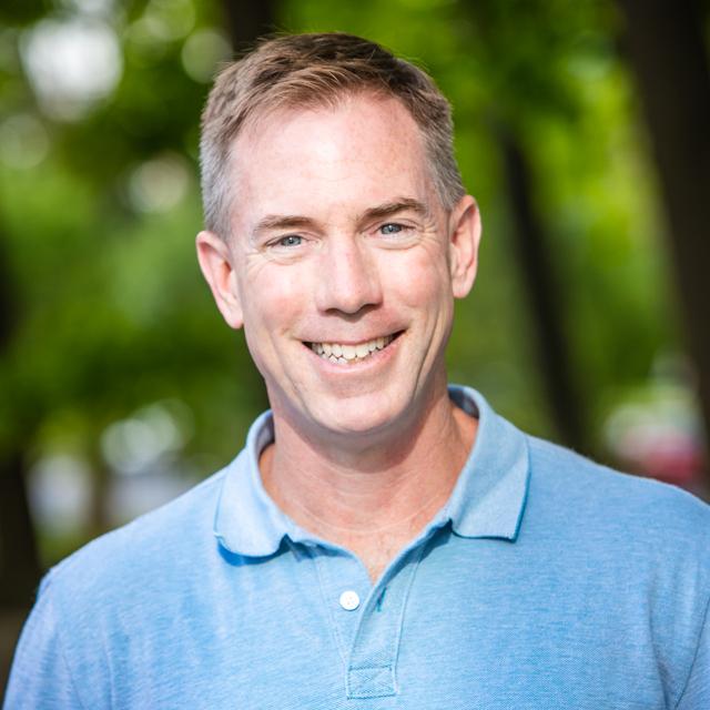 Dr. Stephen LeBlanc is pictured smiling standing in front of a green field.