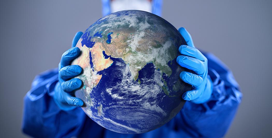 Person with a mask holding a world globe (iStock credit_ hocus-focus