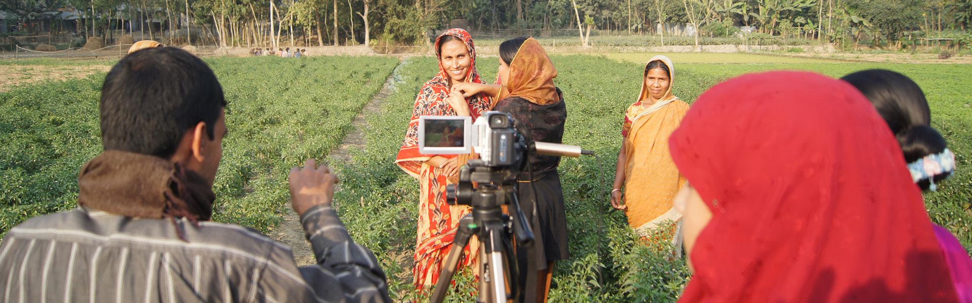 Videographers stand in field with farmers