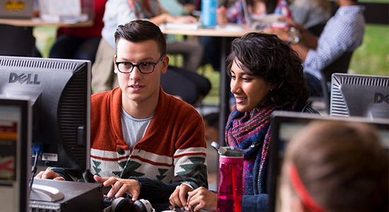 Two students sitting at a computer in the library