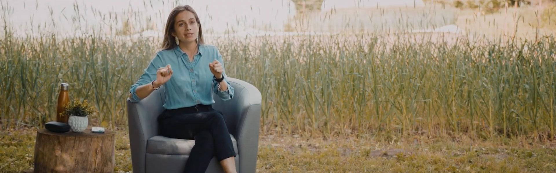 Margarita sitting in chair with tall grass behind her