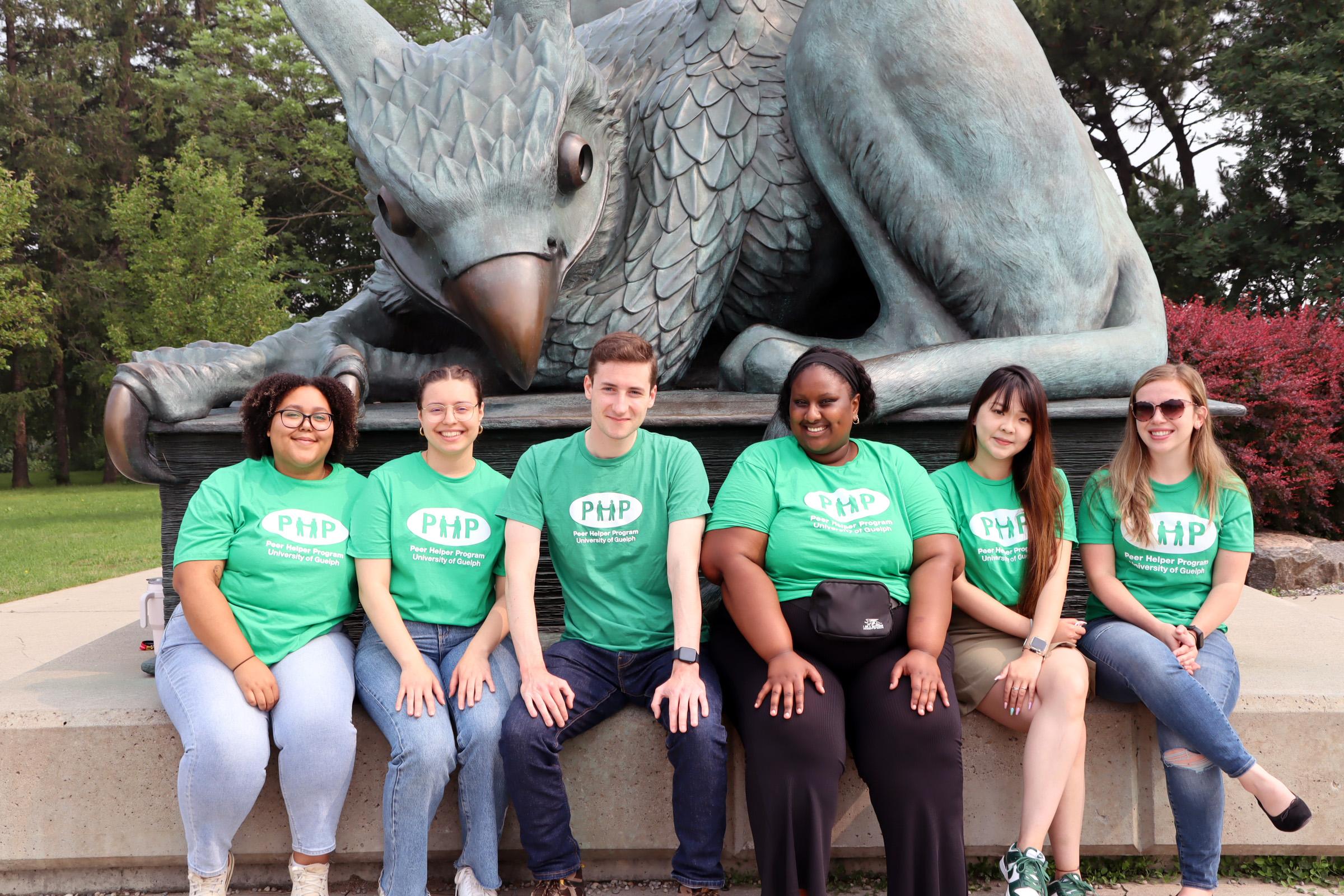 Students in Peer Helper T-shirts sitting in front of the Gryphon statue