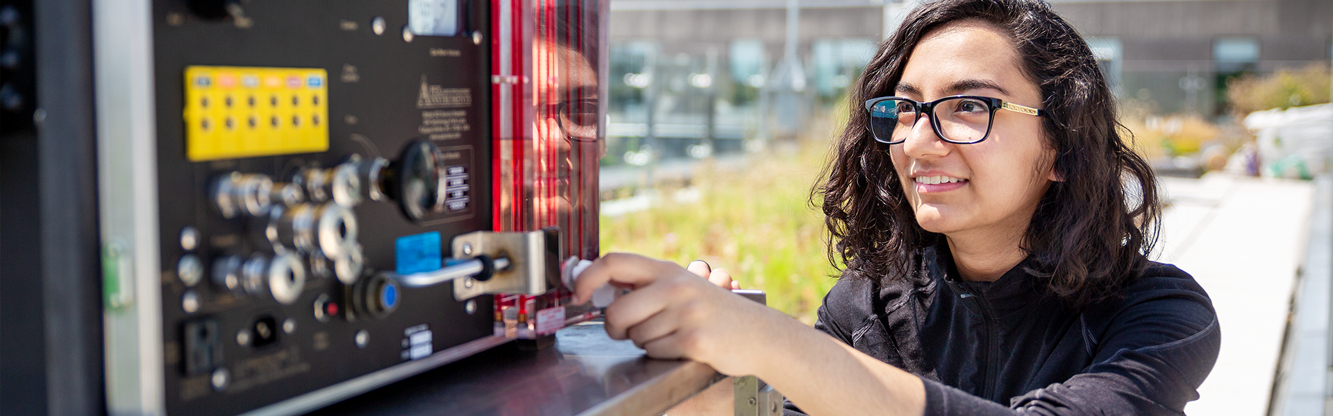 Female student adjusting a knob on a wind-reading device