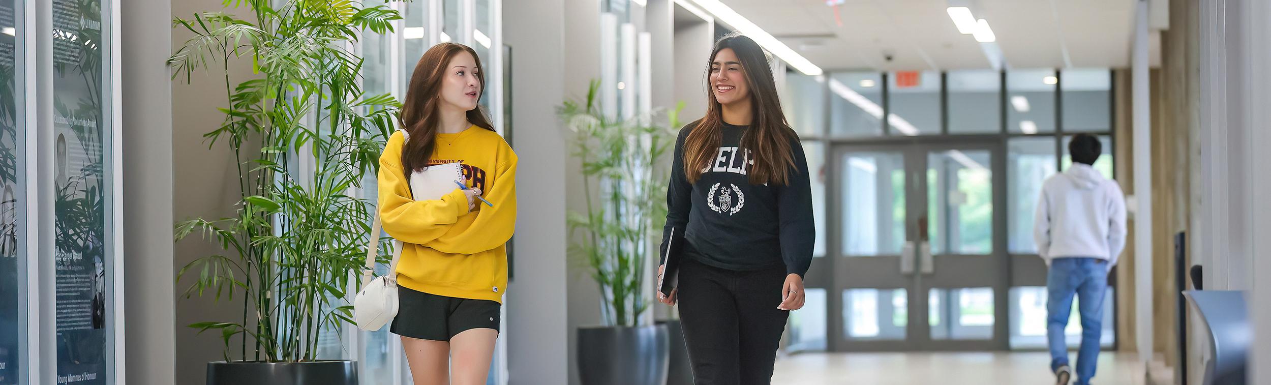 Two students walk together while chatting and laughing in the engineering building.