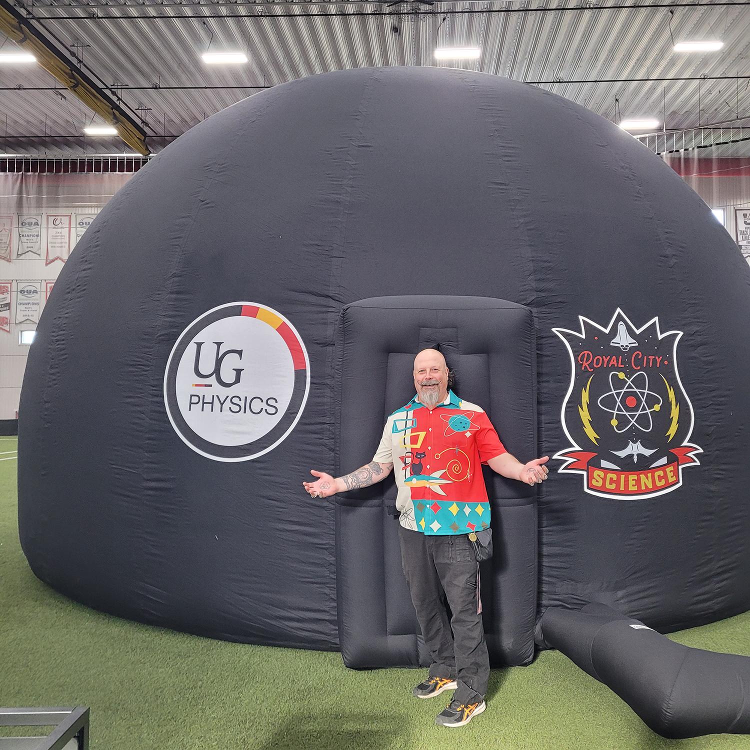 man standing with arms out to his side in front of an inflatable dome