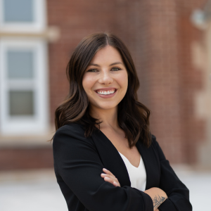 Women in a white top and a black blazer with her arms crossed