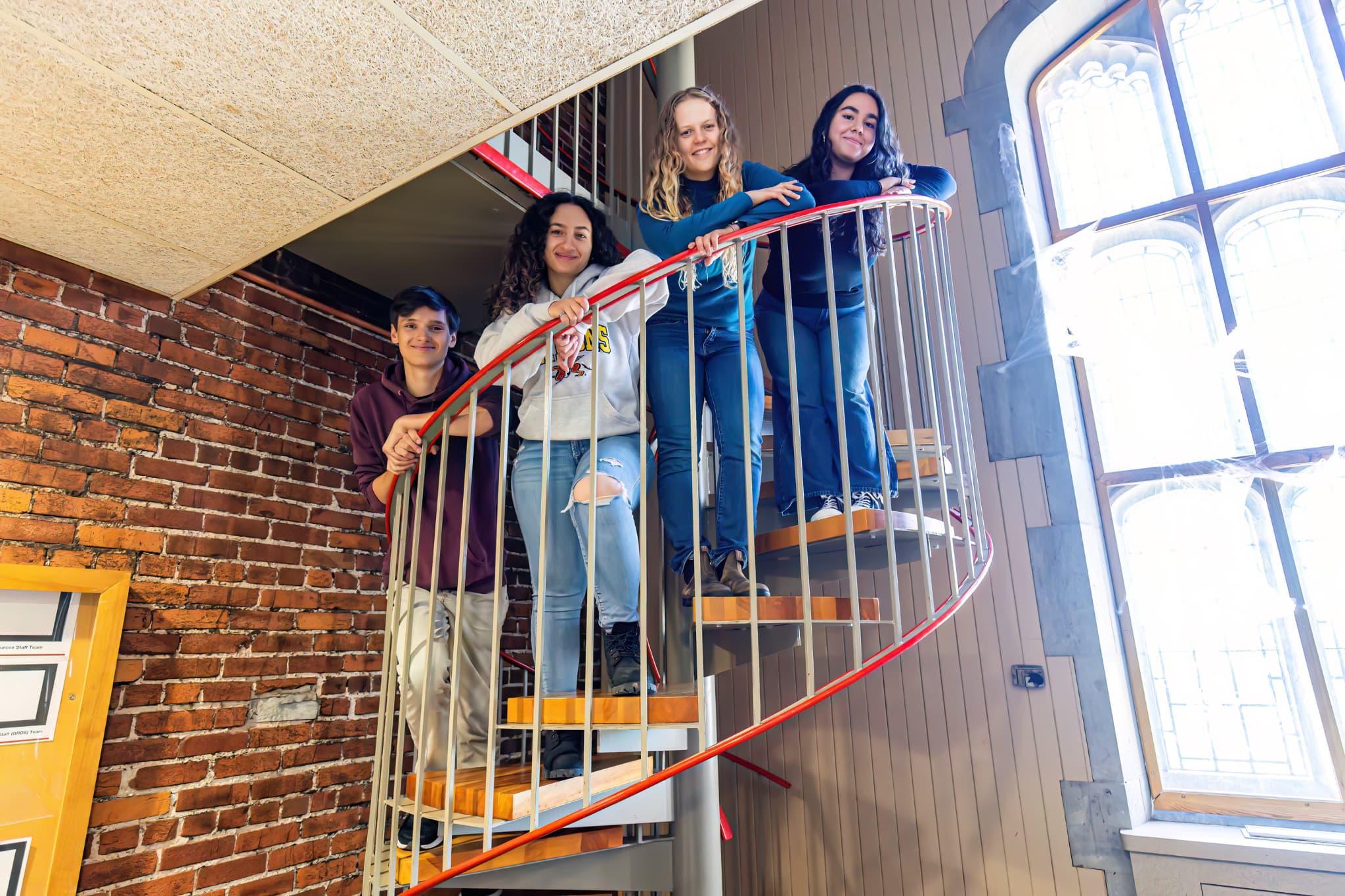 Four students standing around the staircase in Johnston Lounge